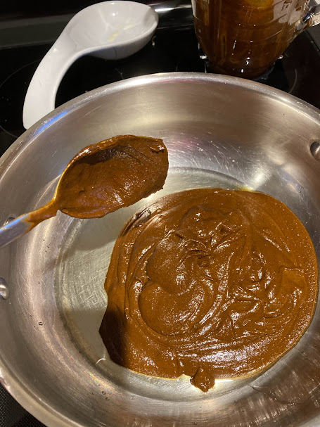 mole sauce and a spoon in a saucepan with oil